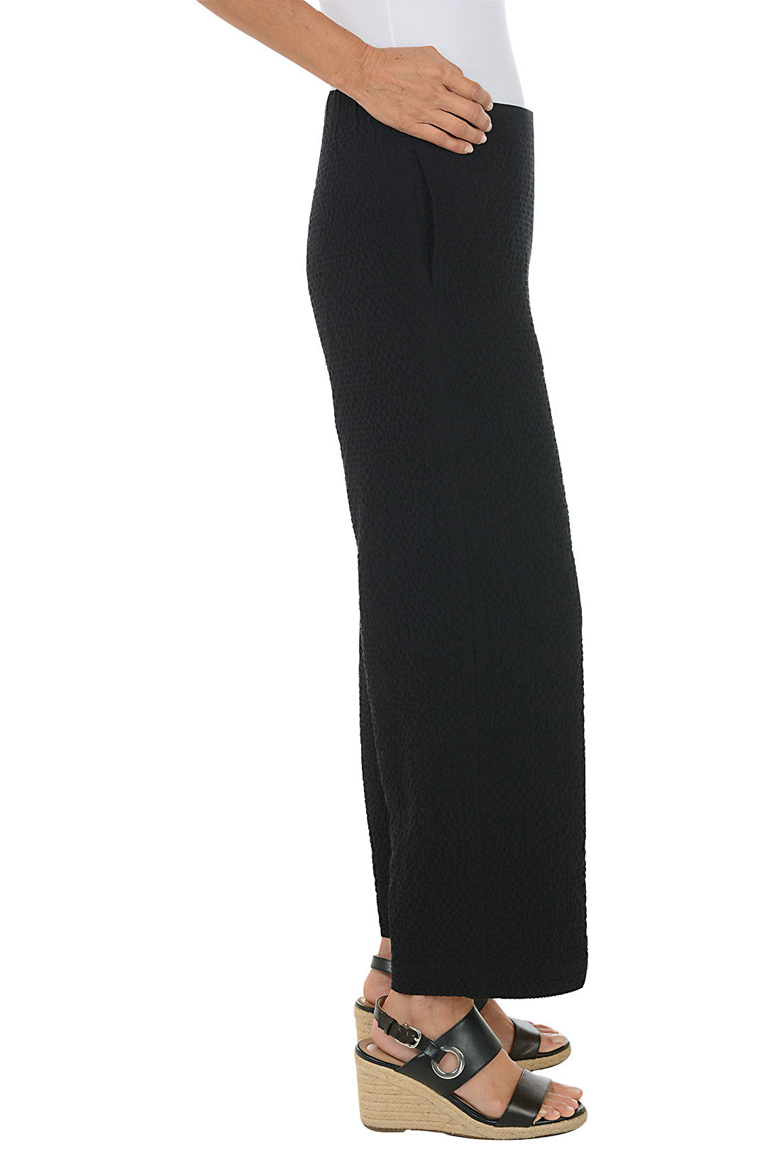 Person wearing black wide-leg pants on a white background. Side shot.