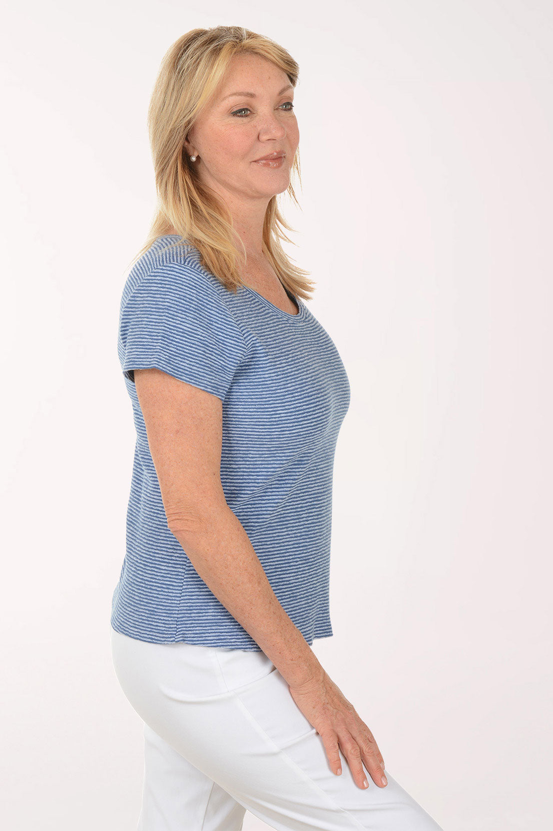 Woman wearing a blue striped shirt and white pants on a white background