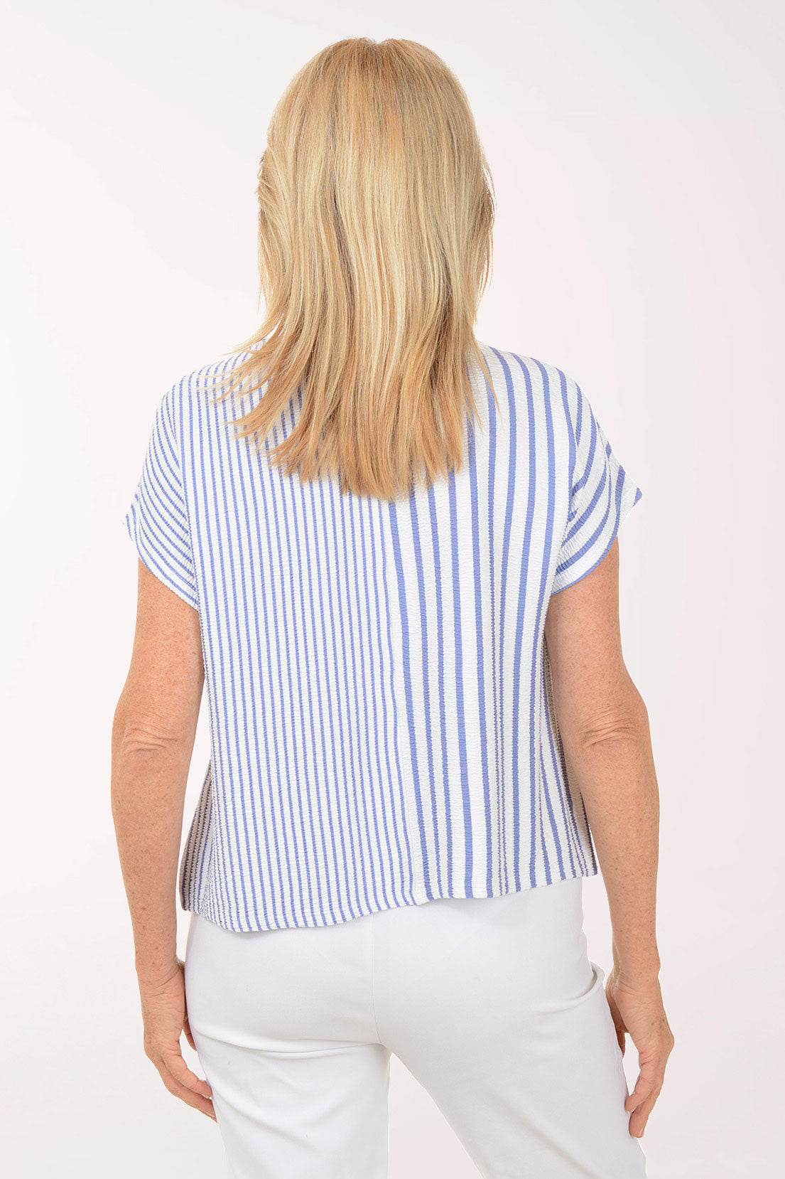 Woman wearing a blue and white striped top and white pants on a white background