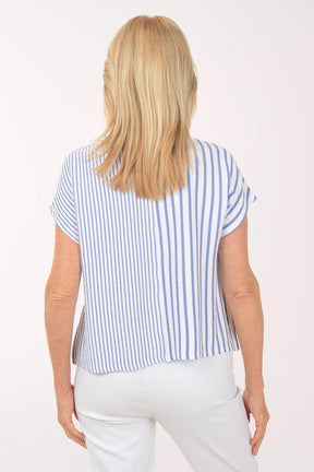 Woman wearing a blue and white striped top and white pants on a white background