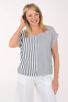 Woman wearing a navy and white striped top and white pants on a white background