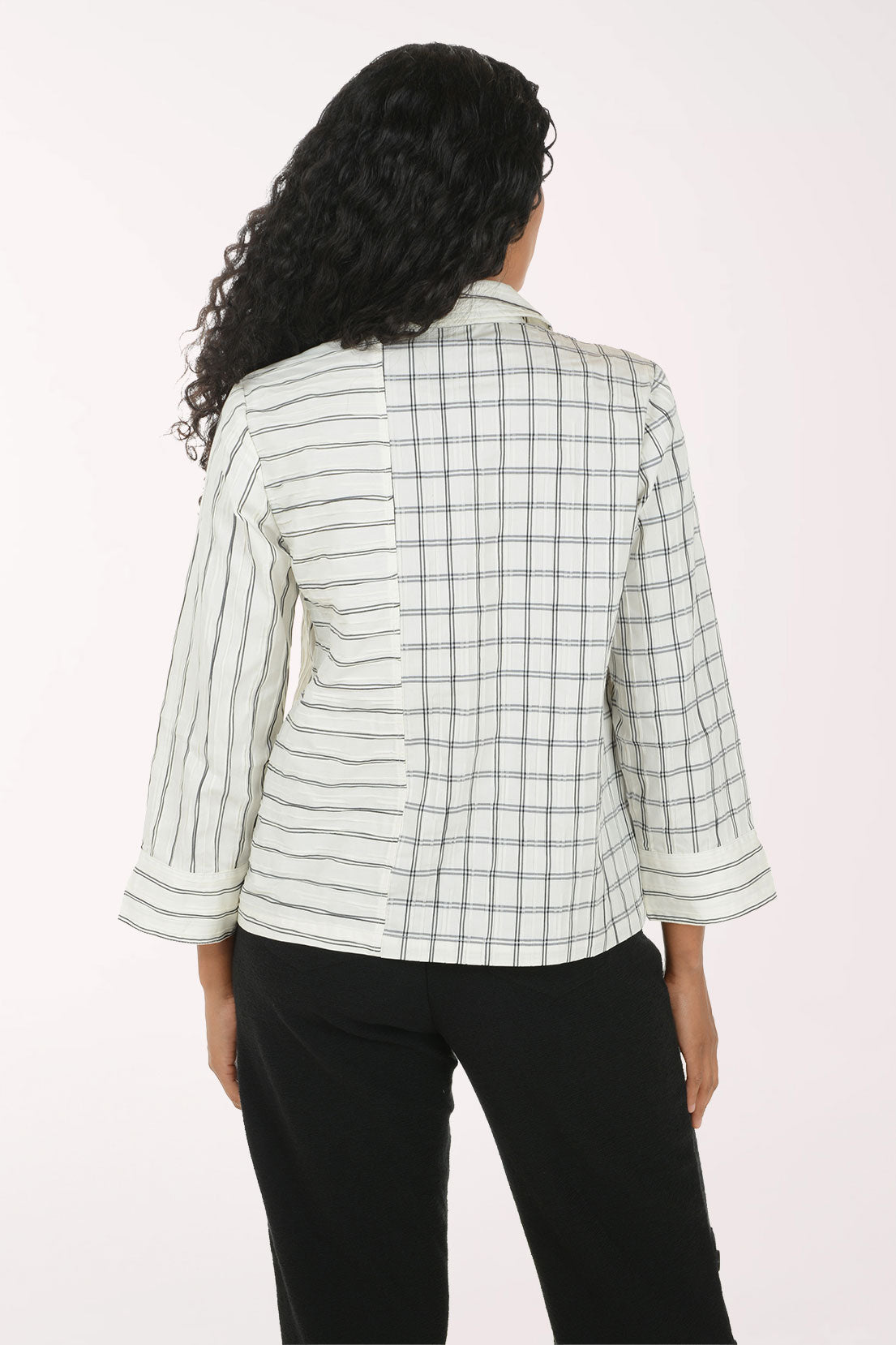 A woman shown from the back wearing a light green and white striped plaid blazer with three-quarter sleeves, paired with black pants, against a plain off-white background.