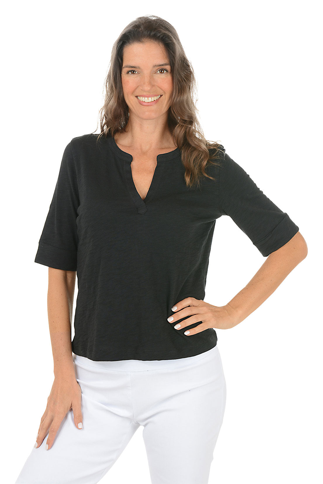 Woman wearing a black elbow sleeve top and white pants on a white background.