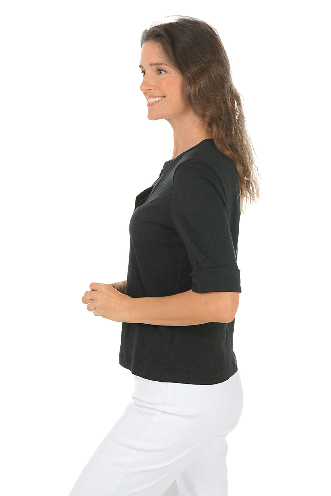 Woman wearing a black elbow sleeve top and white pants on a white background. Side shot.