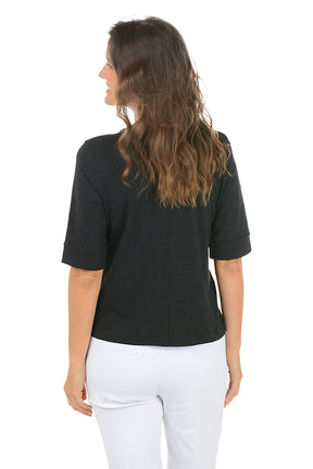Woman wearing a black elbow sleeve top and white pants on a white background. Back shot.
