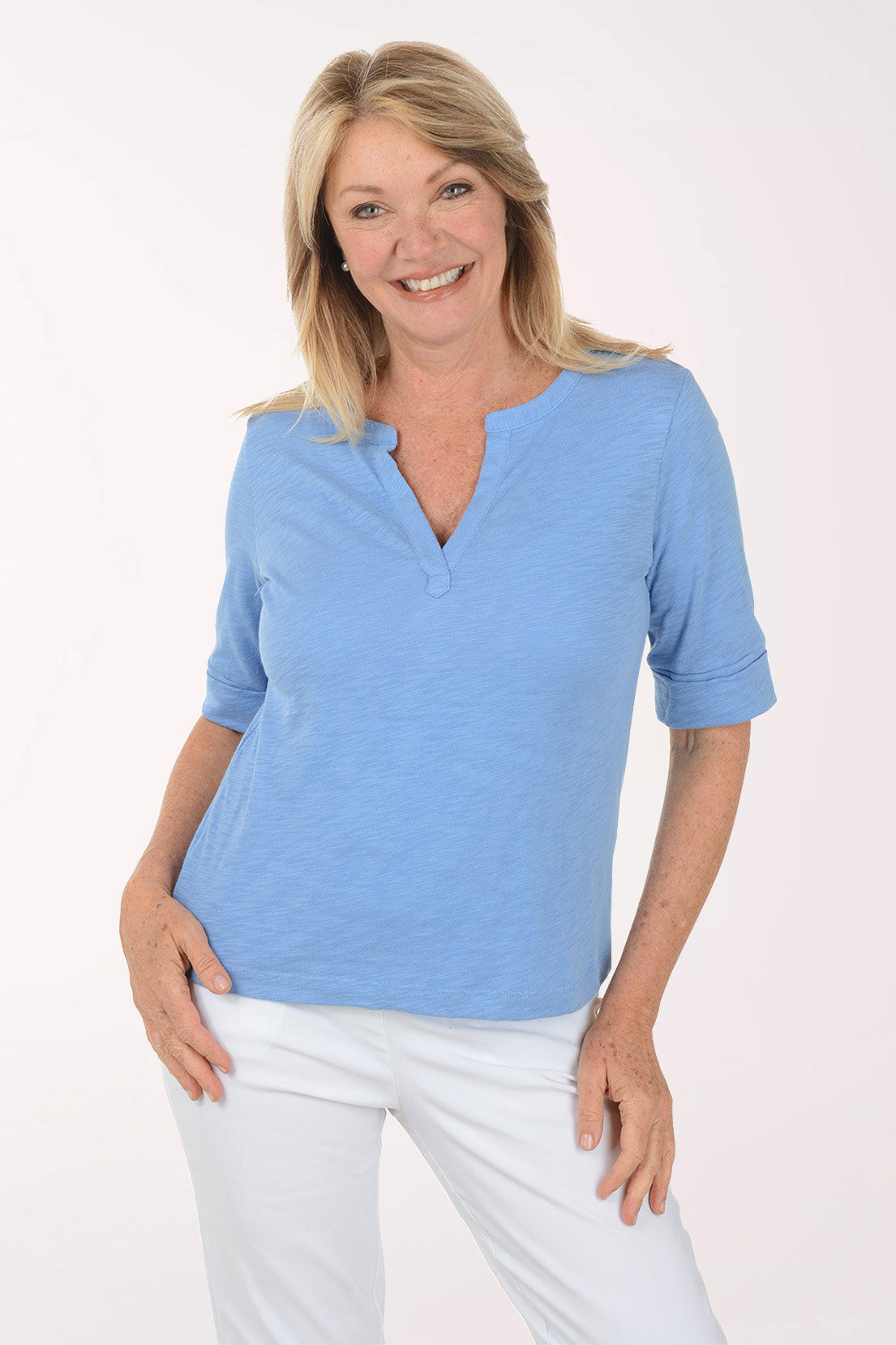 Woman wearing a blue top and white pants on a white background