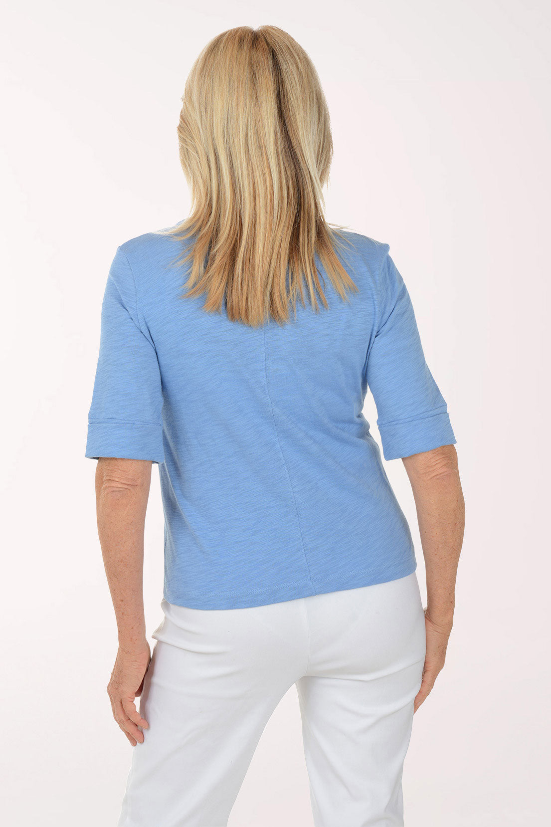 Woman wearing a blue top and white pants on a white background