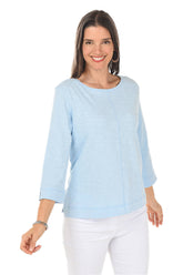 Woman wearing a light blue top and white pants on a white background