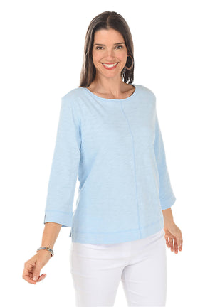 Woman wearing a light blue top and white pants on a white background