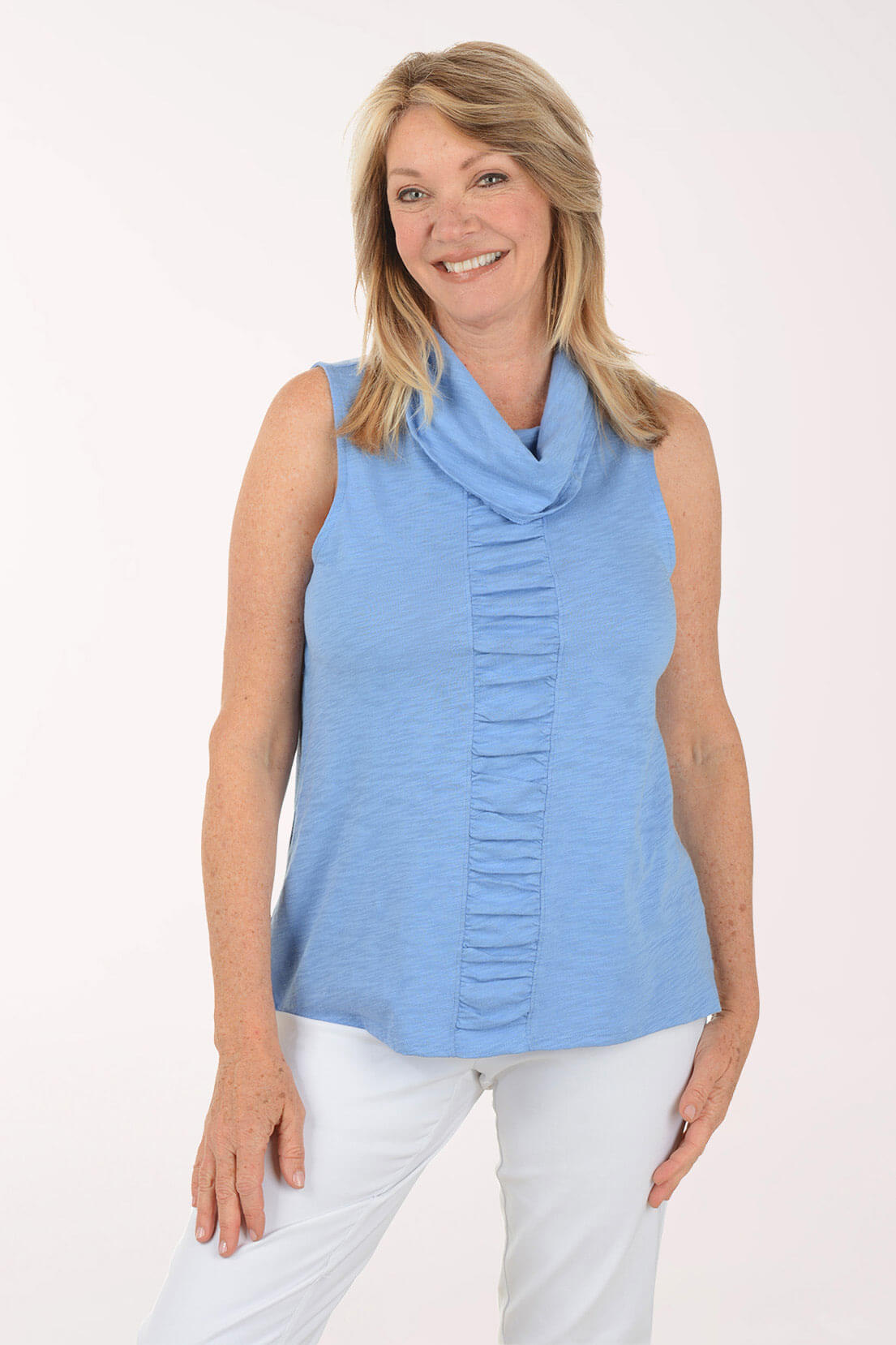 Woman wearing a blue sleeveless top with a cowl neck and pleated front on a white background