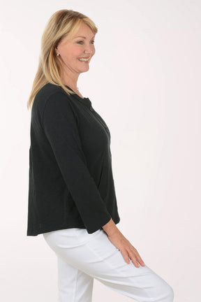 Woman wearing a black cardigan and white pants on a white background