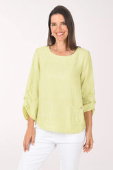 Woman wearing a light green blouse and white pants on a white background