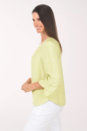 Woman wearing a light green blouse and white pants on a white background