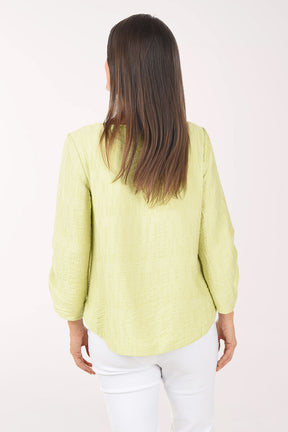 Woman wearing a light green blouse and white pants on a white background