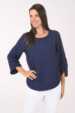 Woman wearing a navy blue sweater and white pants on a white background