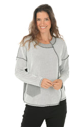 Woman wearing a gray patterned top with black stitching on a white background.