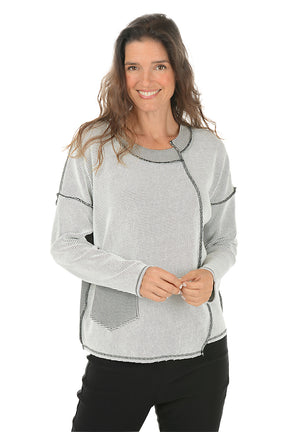 Woman wearing a gray patterned top with black stitching on a white background.