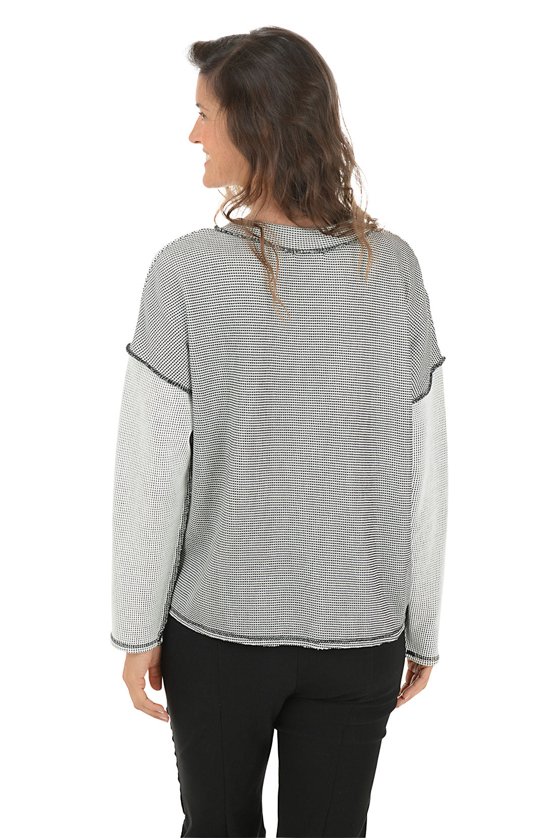 Woman wearing a gray patterned top with black stitching on a white background. Back shot.