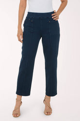A model wearing dark blue cropped straight-leg jeans, paired with a white top and beige strappy high-heeled sandals, shown from the waist down against a plain white studio background.