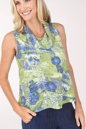 Woman wearing a sleeveless floral top and navy pants on a white background