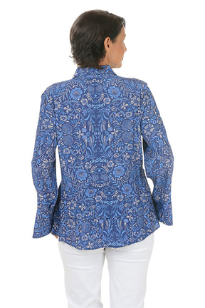 Woman wearing a blue patterned blouse and white pants on a white background. Back shot.