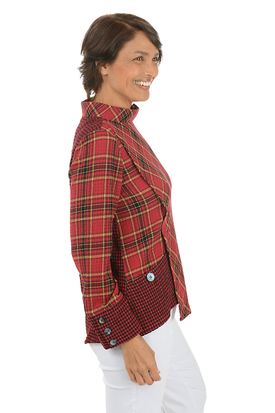 Woman wearing a contrasting plaid red and yellow shirt and white pants on a white background. Side shot.