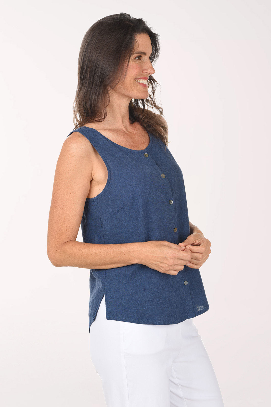 Woman wearing a blue sleeveless top with buttons on a white background