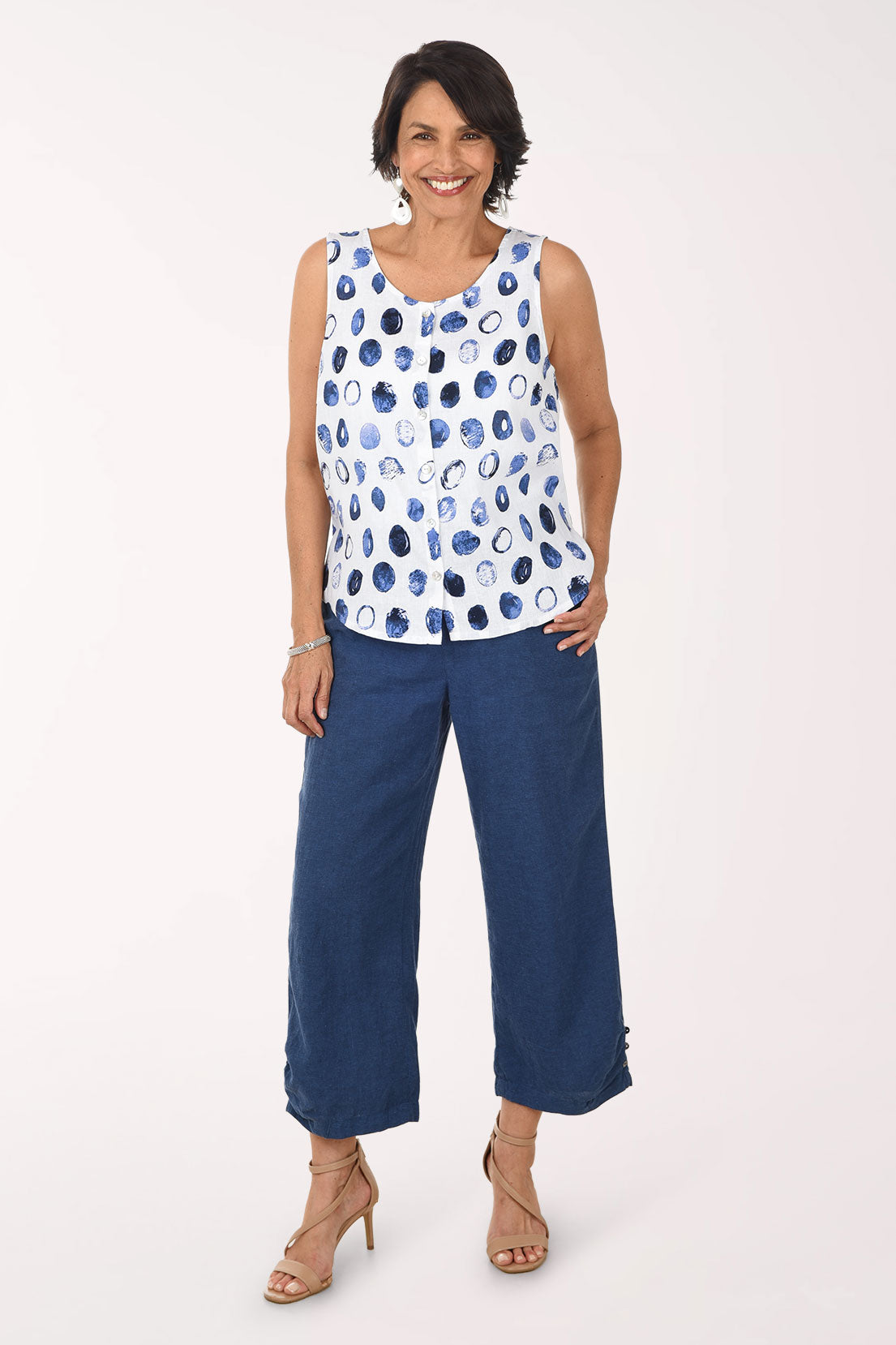 Woman wearing a sleeveless top with blue and white pattern and blue pants on a white background