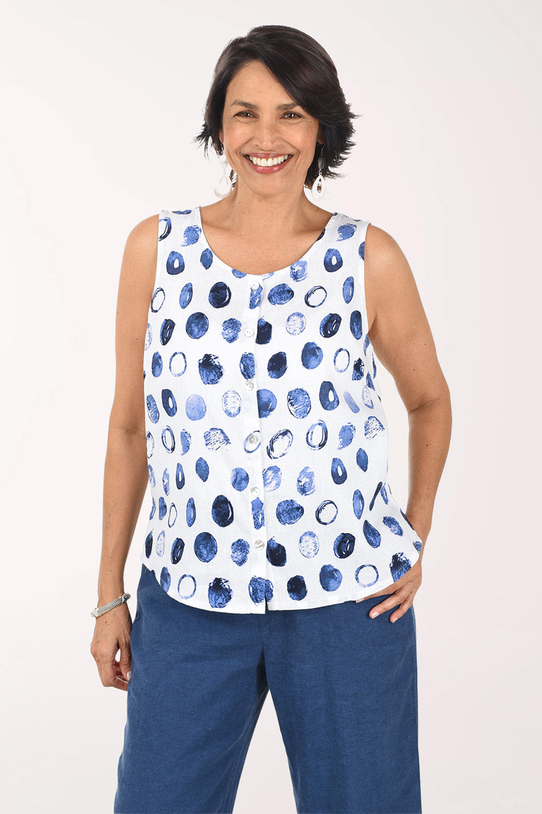 Woman wearing a sleeveless top with blue abstract pattern and blue pants on a white background