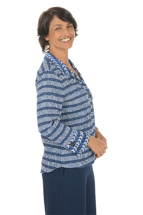 Woman wearing a blue patterned blouse on a white background. Side shot.