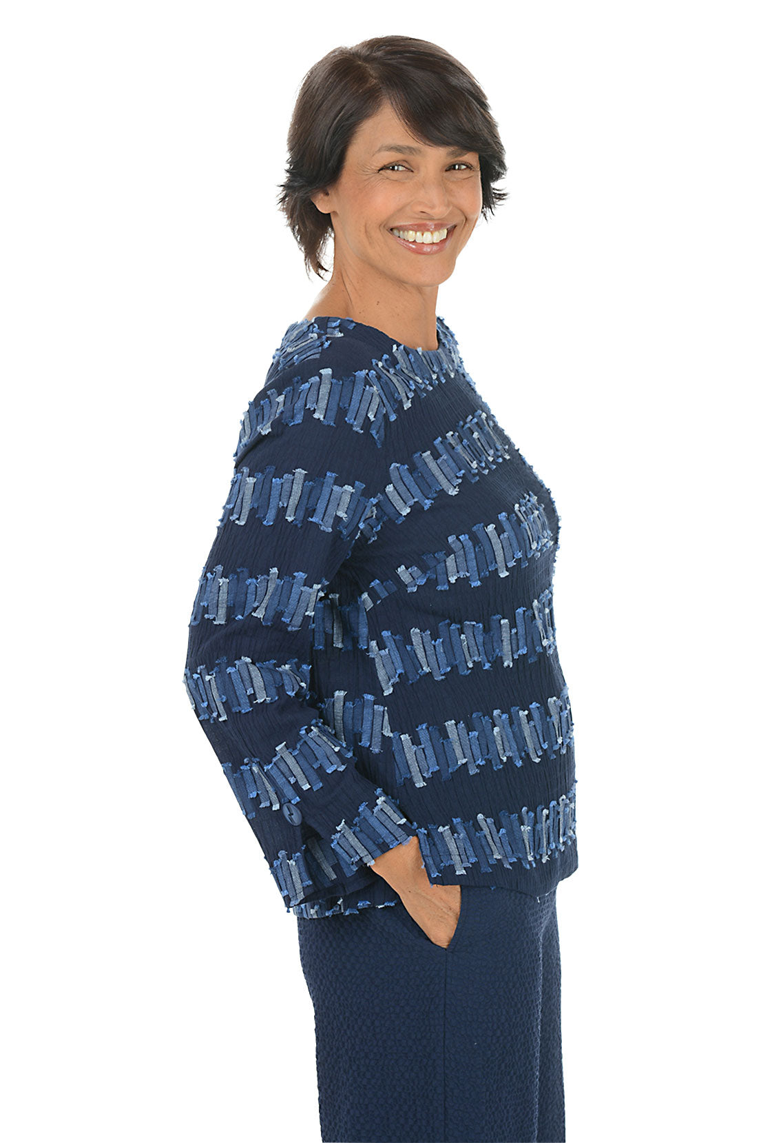 Woman wearing a blue patterned 3/4 sleeve top on a white background. Side shot.