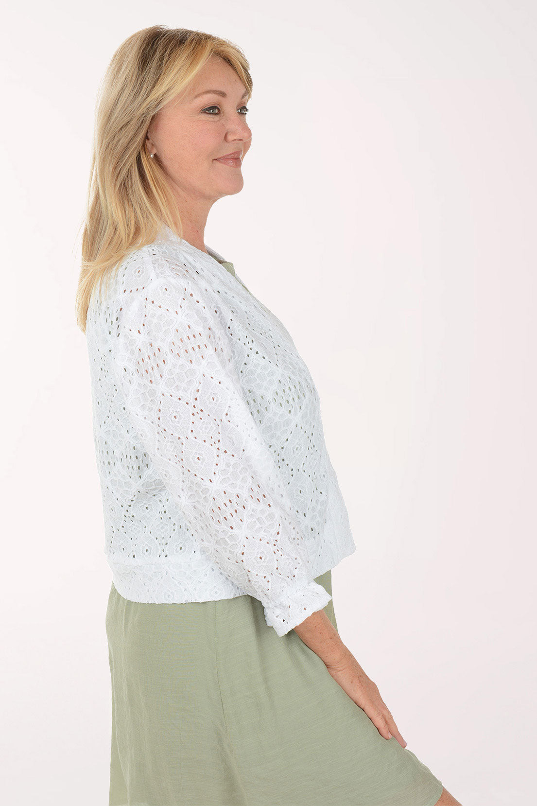 Woman wearing a white lace shrug over a green dress on a white background