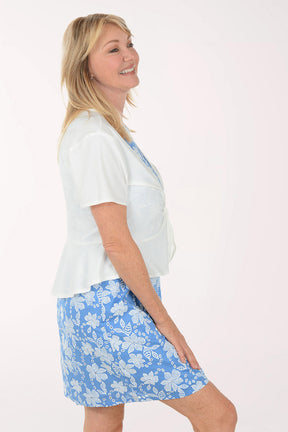 Woman wearing a white shrug top and blue floral dress on a white background