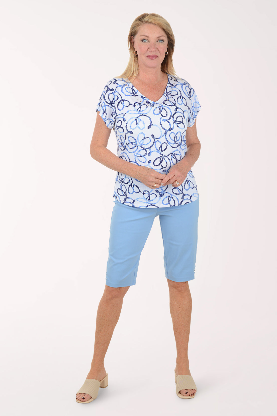 Woman wearing a blue and white patterned top with light blue shorts on a white background