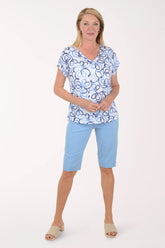 Woman wearing a blue and white patterned top with light blue shorts on a white background