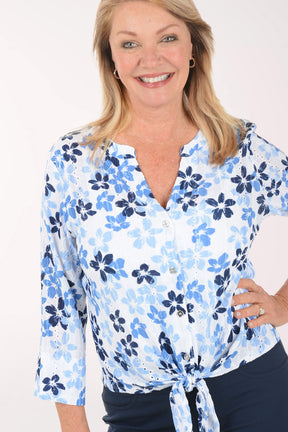 Woman wearing a blue floral blouse and navy shorts on a white background