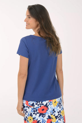 Woman wearing a blue top and floral skirt on a white background