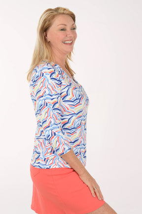 Woman wearing a colorful patterned top and coral skirt on a white background