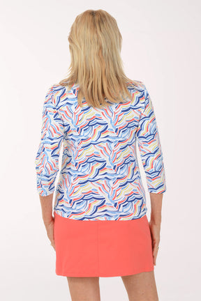 Woman wearing a colorful patterned top and coral skirt on a white background