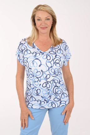 Woman wearing a blue and white patterned top with light blue pants on a white background