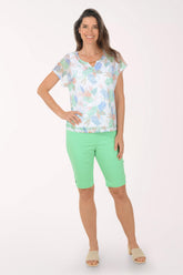 Woman wearing a patterned top and green shorts on a white background