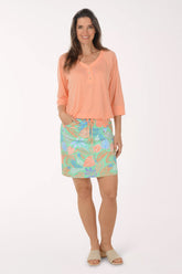 Woman wearing a peach blouse and colorful skirt on a white background