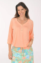 Woman wearing a peach-colored long-sleeve top with a floral skirt on a white background