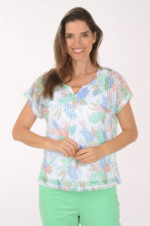 Woman wearing a colorful patterned top and green pants on a white background