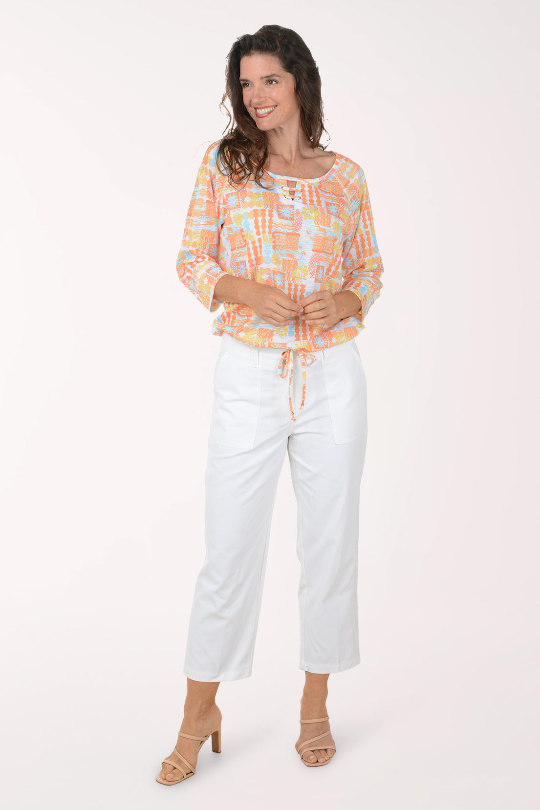 Woman wearing a colorful blouse and white pants on a white background