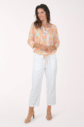 Woman wearing a colorful blouse and white pants on a white background