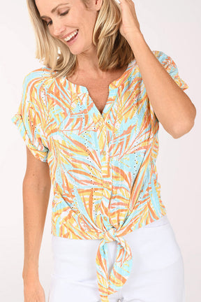 Woman wearing a short sleeve multi colored top with a tie detail on the hem.