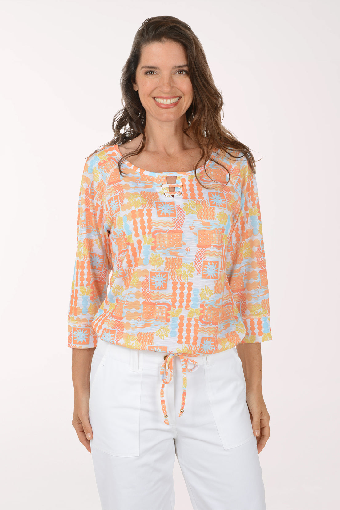 Woman wearing a colorful patterned top and white pants on a white background