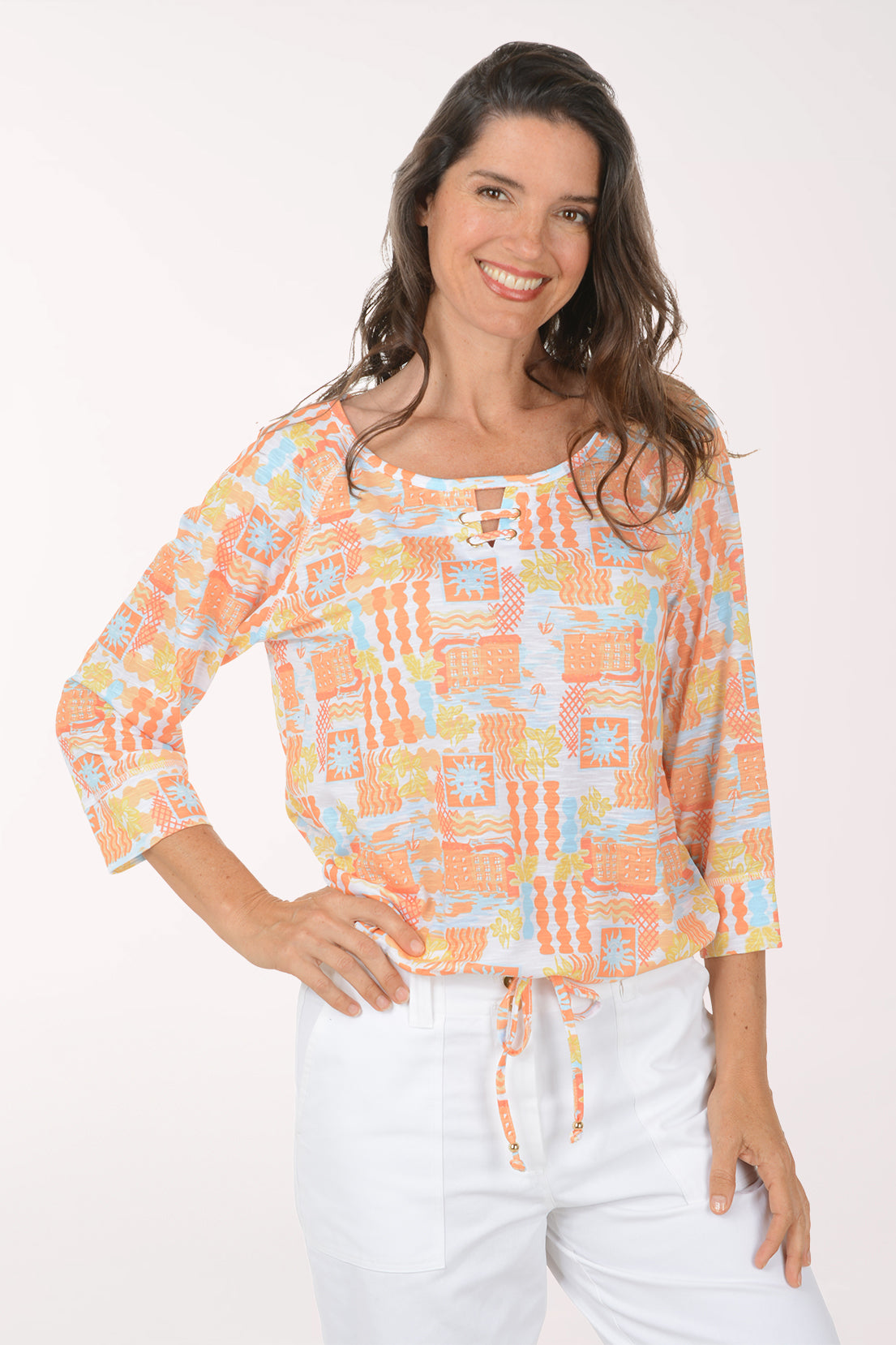 Woman wearing a colorful patterned top and white pants on a white background