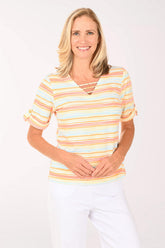 Woman wearing a colorful striped shirt and white pants on a white background